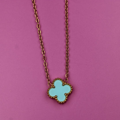 Necklace with a turquoise clover-shaped pendant on a pink background