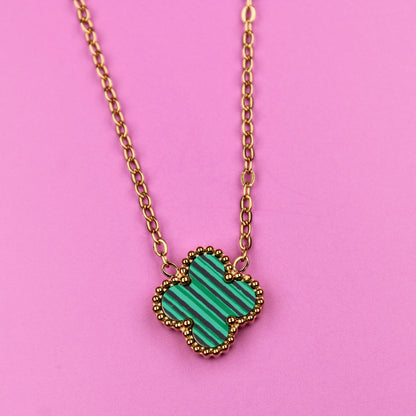 Necklace with a green heart-shaped pendant on a pink background