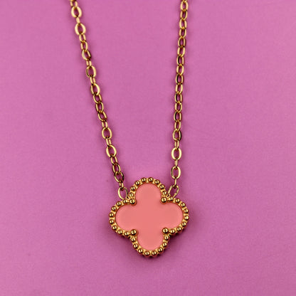 Pink clover-shaped pendant on a gold chain against a pink background