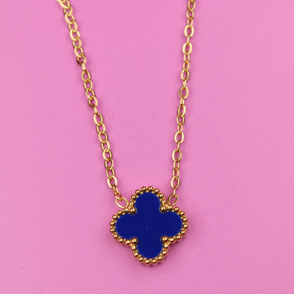 Gold necklace with a blue clover pendant on a pink background