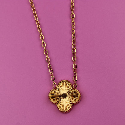 Gold necklace with a floral pendant on a pink background