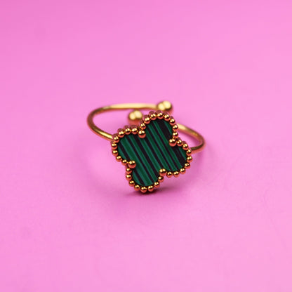 Gold ring with green gemstone on a pink background