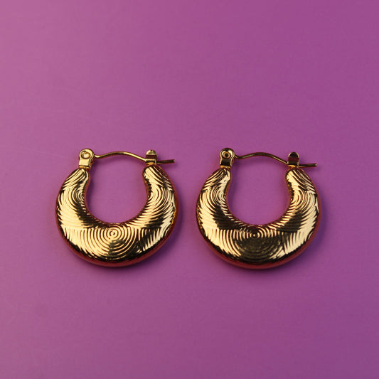 Gold hoop earrings on a purple background