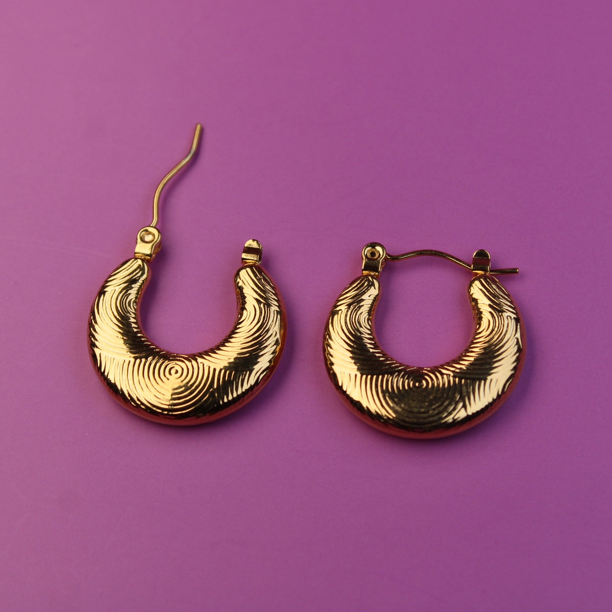 Gold hoop earrings on a purple background