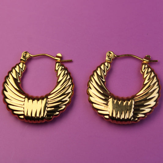Gold hoop earrings on a purple background