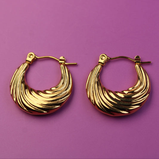 Gold hoop earrings on a purple background