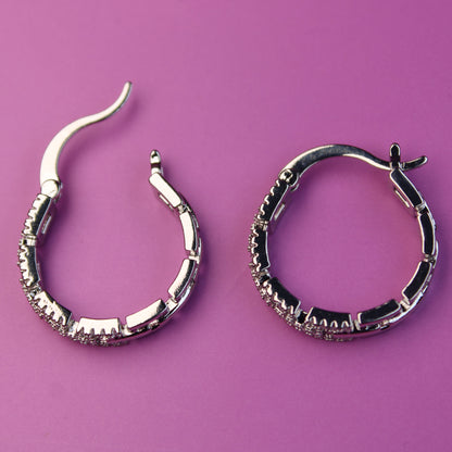Pair of silver hoop earrings on a purple background