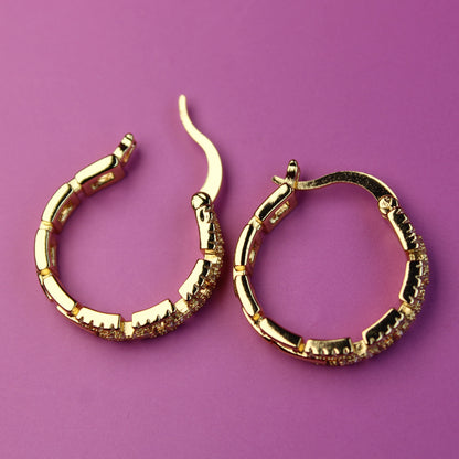 Gold hoop earrings on a purple background