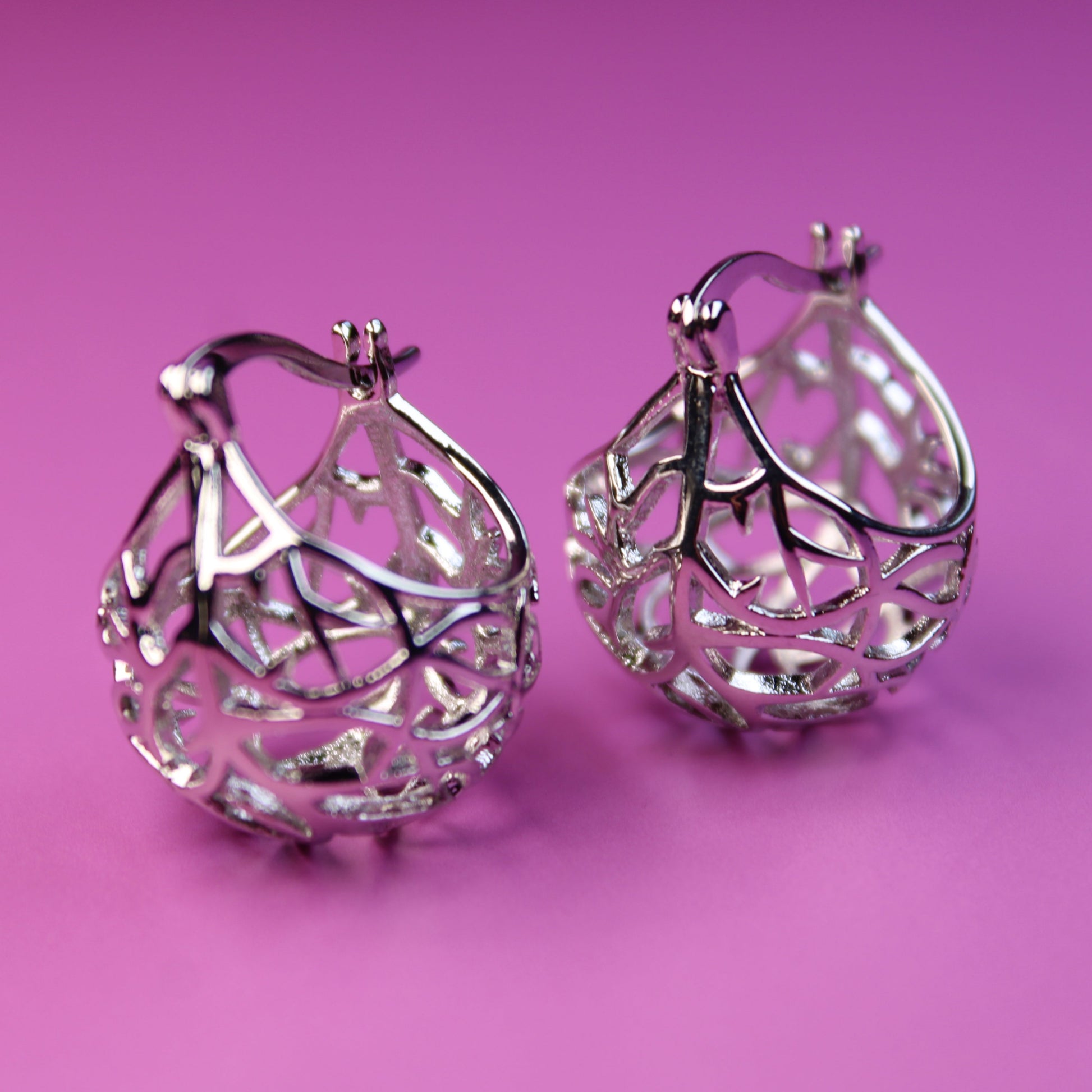 Silver hoop earrings on a pink background