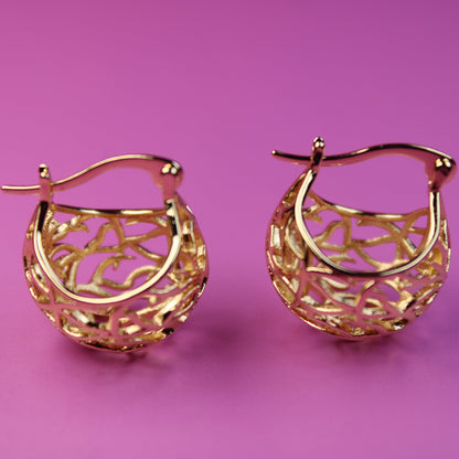 Gold hoop earrings on a pink background