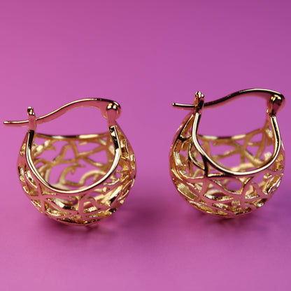 Gold hoop earrings on a pink background
