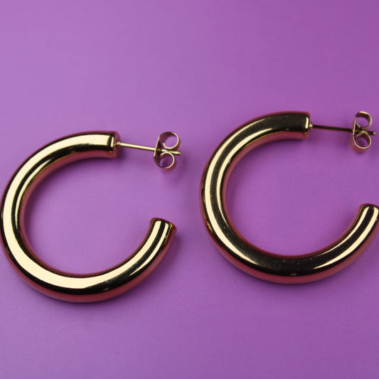 Gold hoop earrings on a purple background