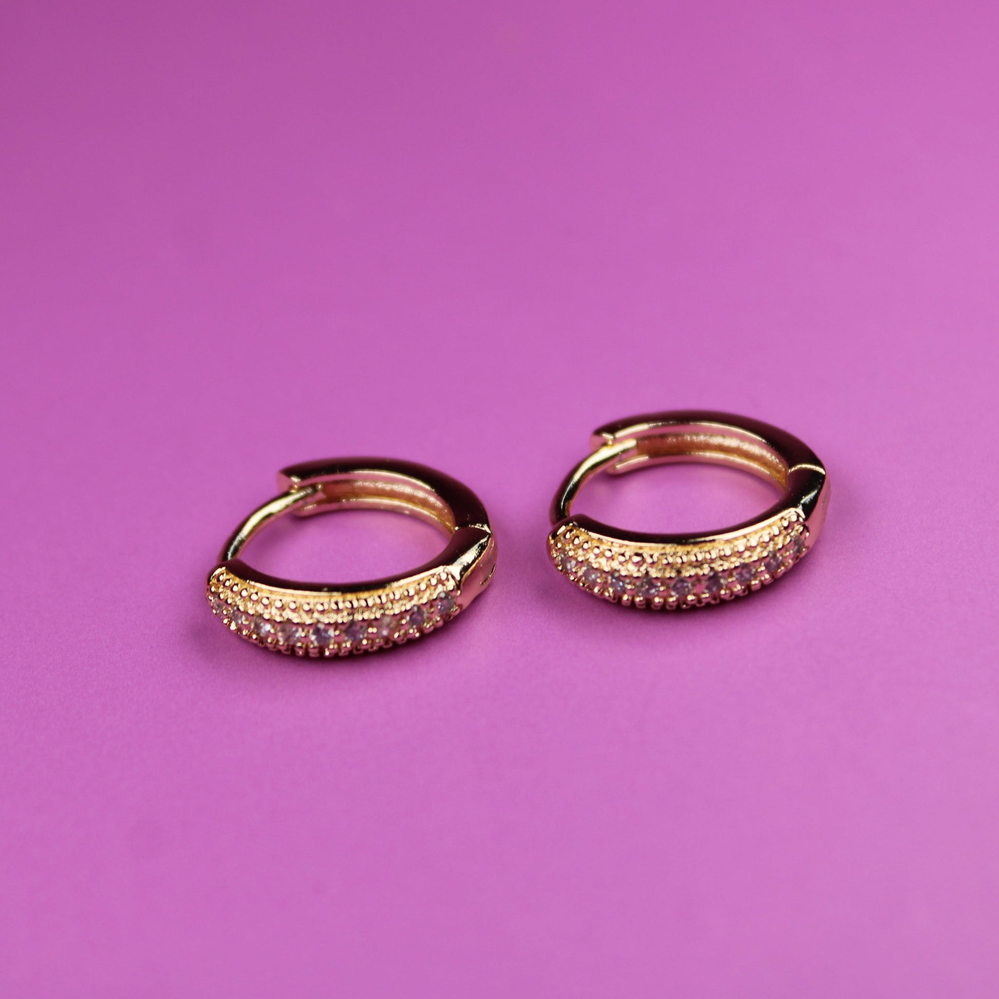 Gold hoop earrings on a pink background