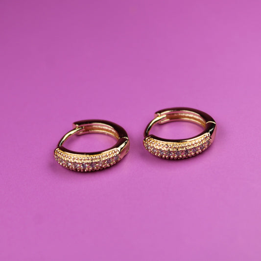 Gold hoop earrings on a pink background