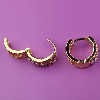 Gold hoop earrings on a purple background