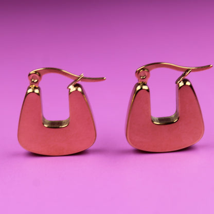 Pair of pink earrings with gold accents on a pink background