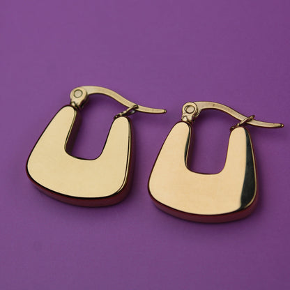 Gold hoop earrings on a purple background