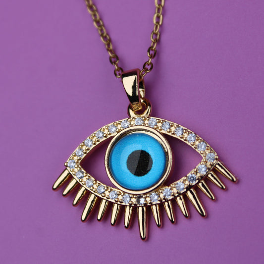 Gold necklace with an eye-shaped pendant on a purple background