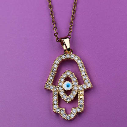 Gold Hamsa hand necklace with diamonds on a purple background