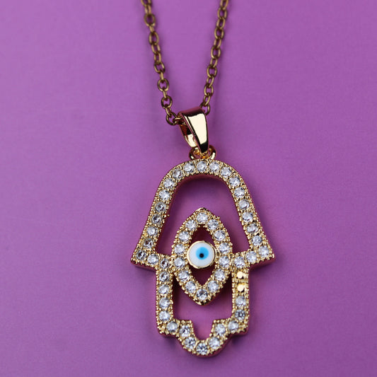 Gold Hamsa hand necklace with diamonds on a purple background