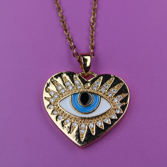 Gold heart-shaped necklace with an eye design on a purple background