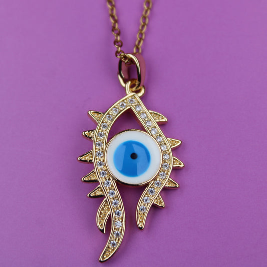 Gold necklace with an eye-shaped pendant on a purple background