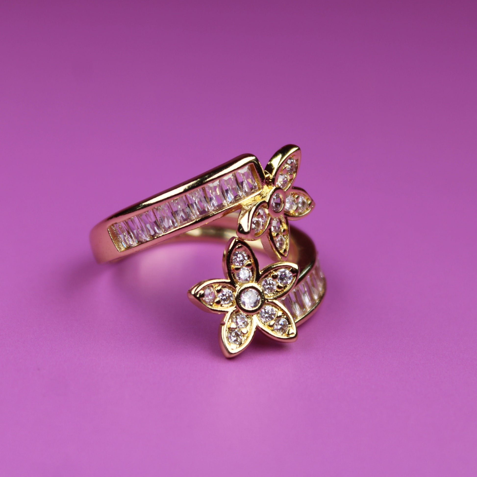 Gold ring with butterfly design on a pink background
