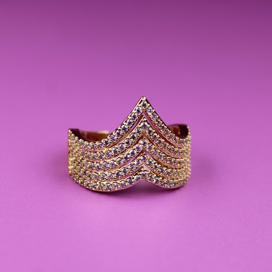Gold bracelet with red accents on a pink background