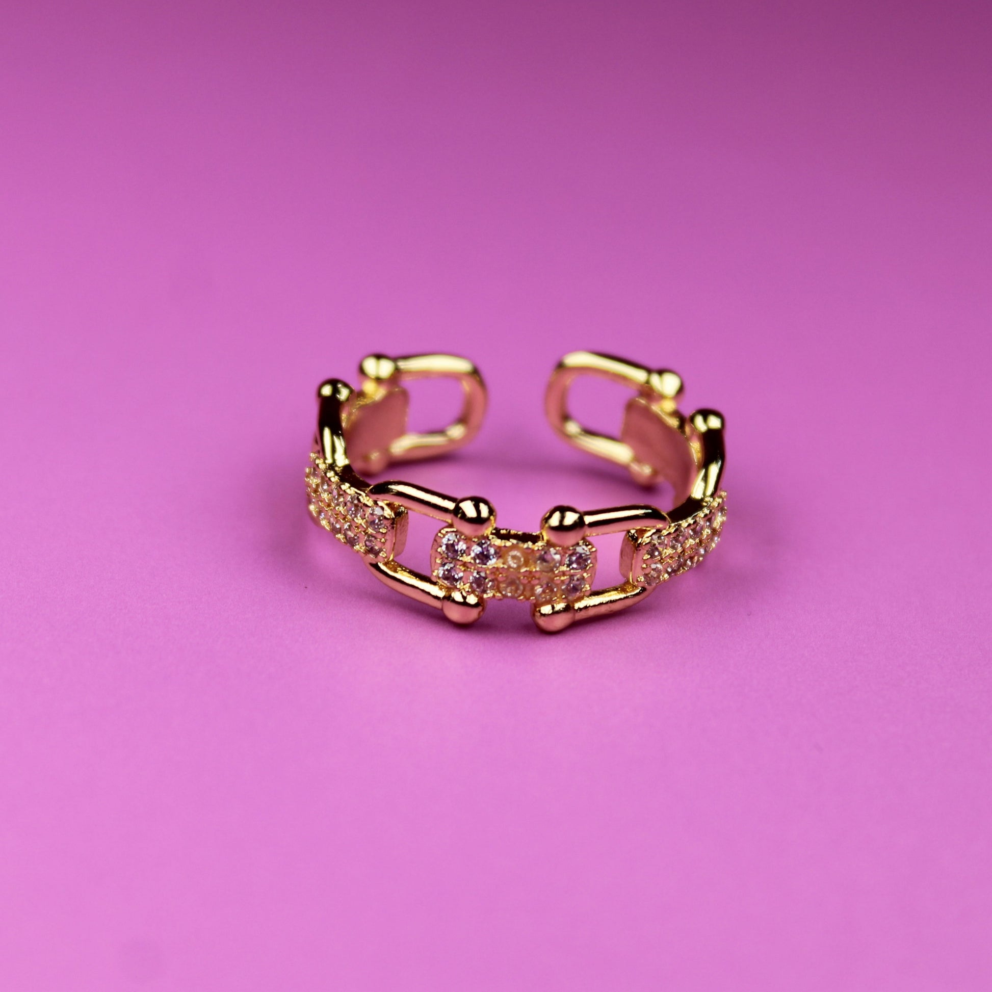 Gold ring with a diamond-like pattern on a pink background