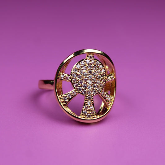 Gold ring with a design on a pink background