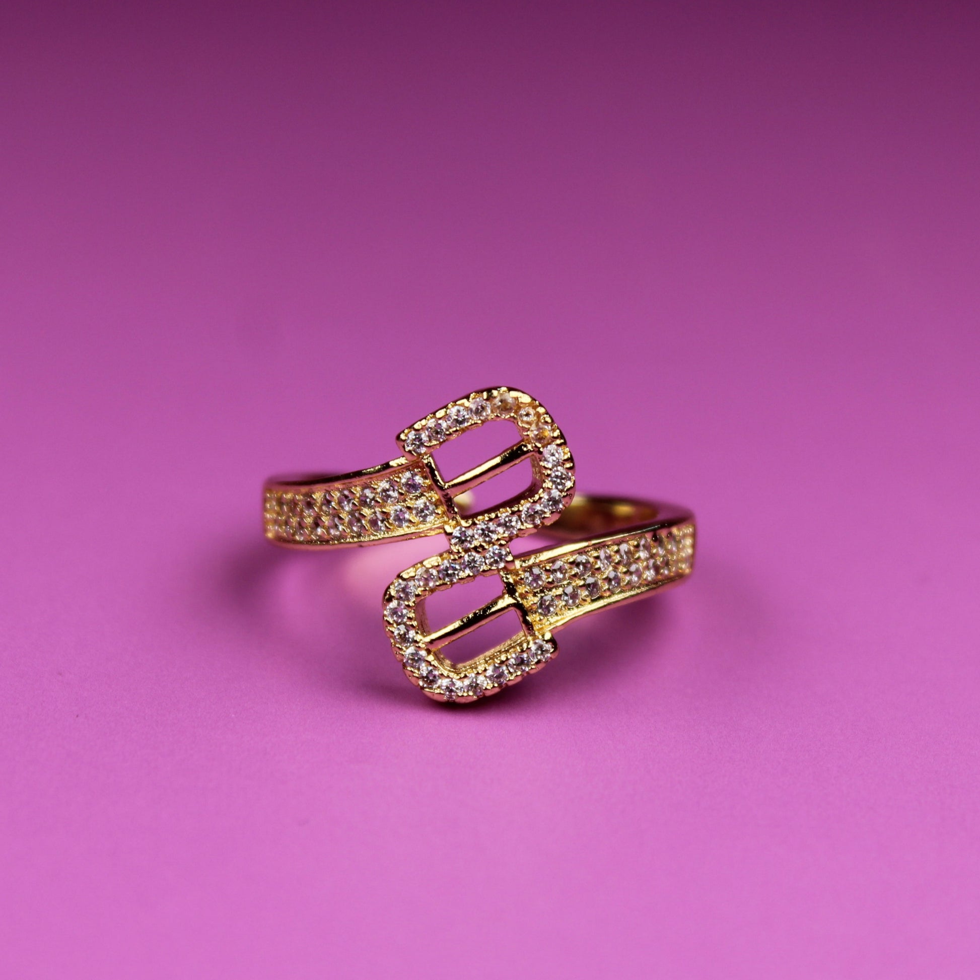 Gold ring with heart design on a pink background