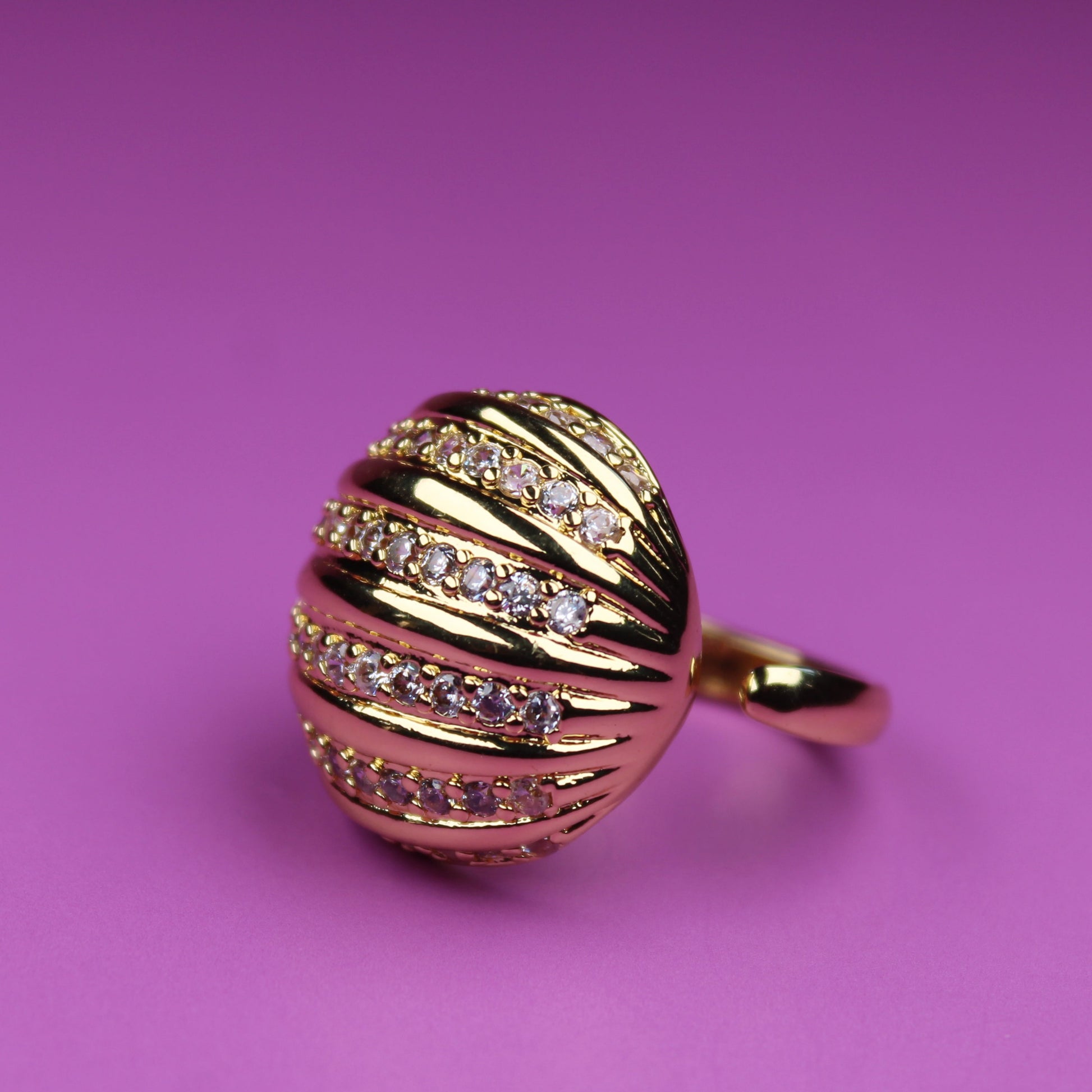 Gold ring with diamond accents on a pink background