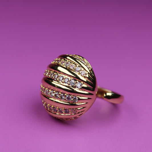 Gold ring with diamond accents on a pink background