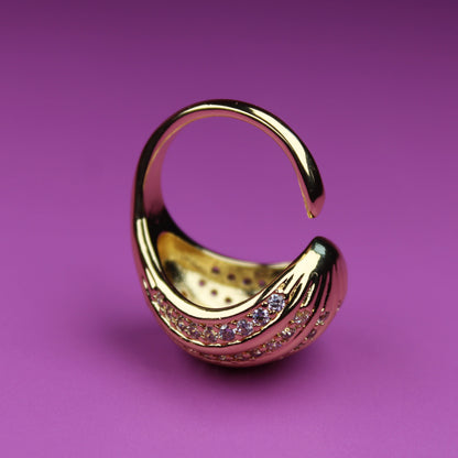 Gold earring with gemstones on a purple background