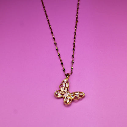 Gold necklace with a cross pendant on a pink background