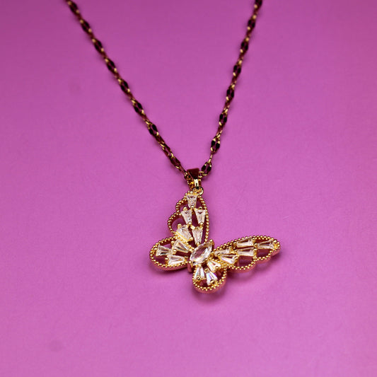 Gold butterfly pendant on a chain against a pink background