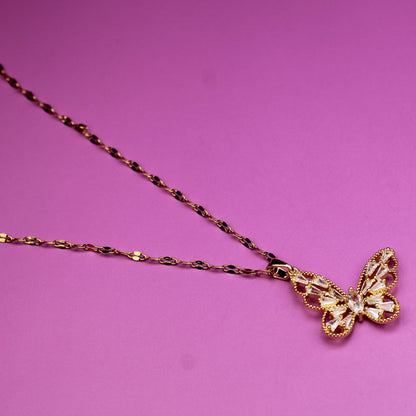 Gold butterfly pendant necklace on a pink background
