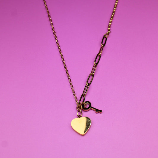Gold necklace with a heart pendant on a pink background