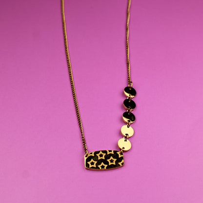 Necklace with leopard print pendant and black and gold beads on a pink background