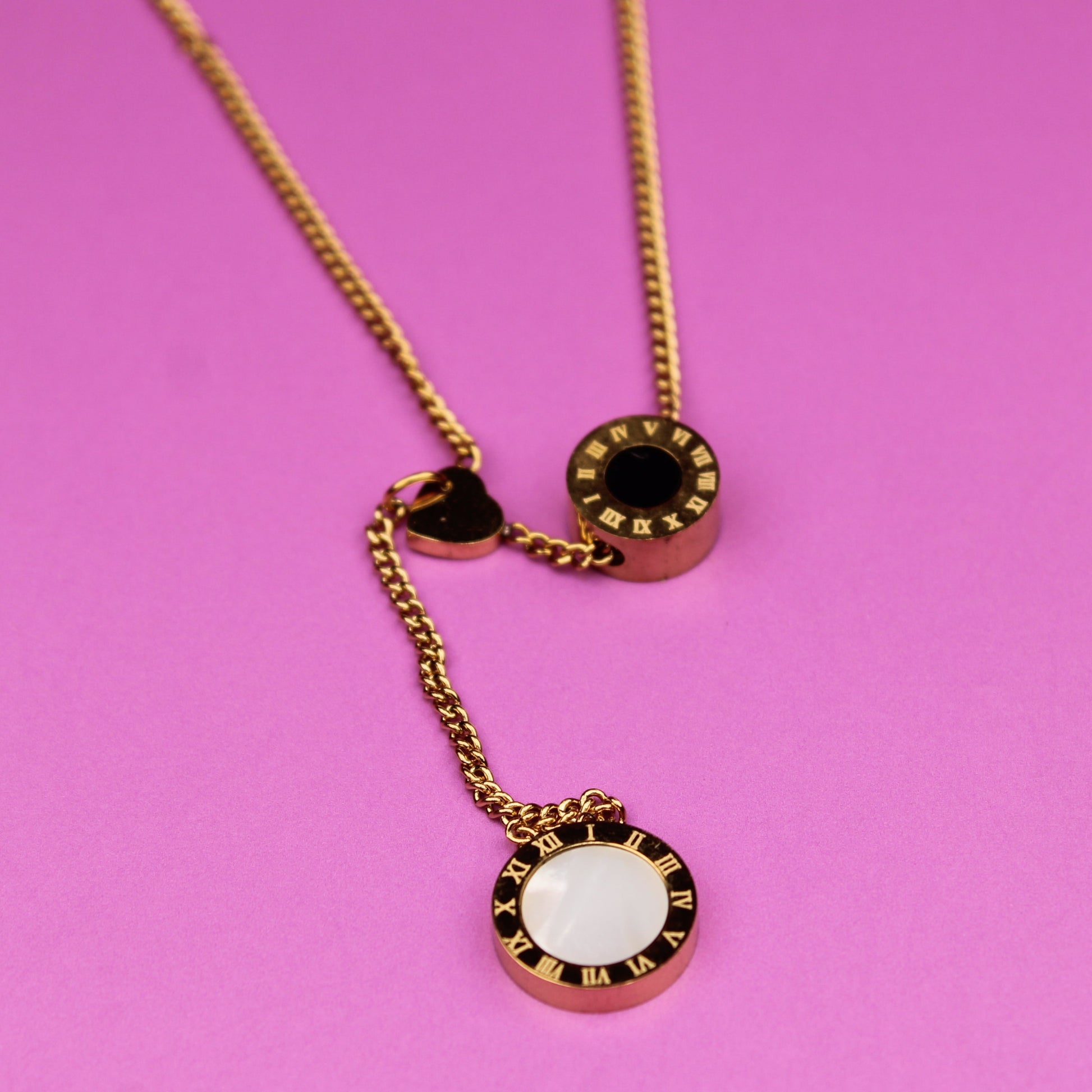 Gold necklace with circular pendant on a pink background