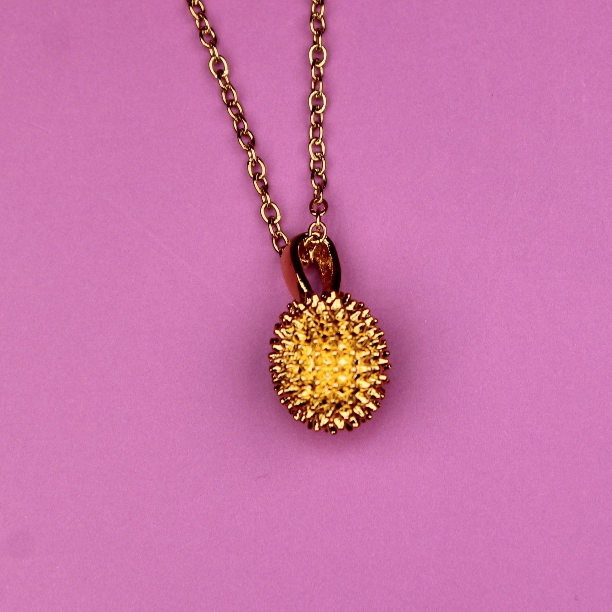 Necklace with a spiky pendant on a pink background
