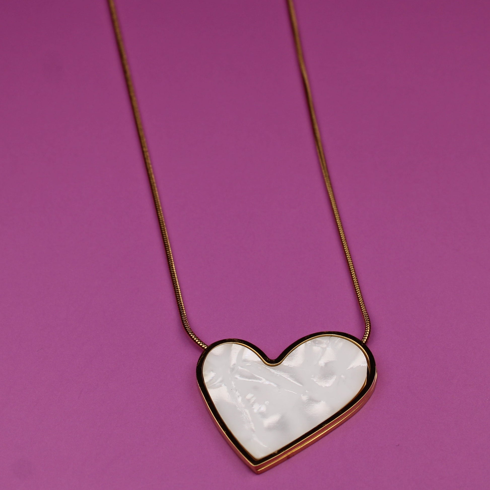 Heart-shaped pendant necklace on a pink background