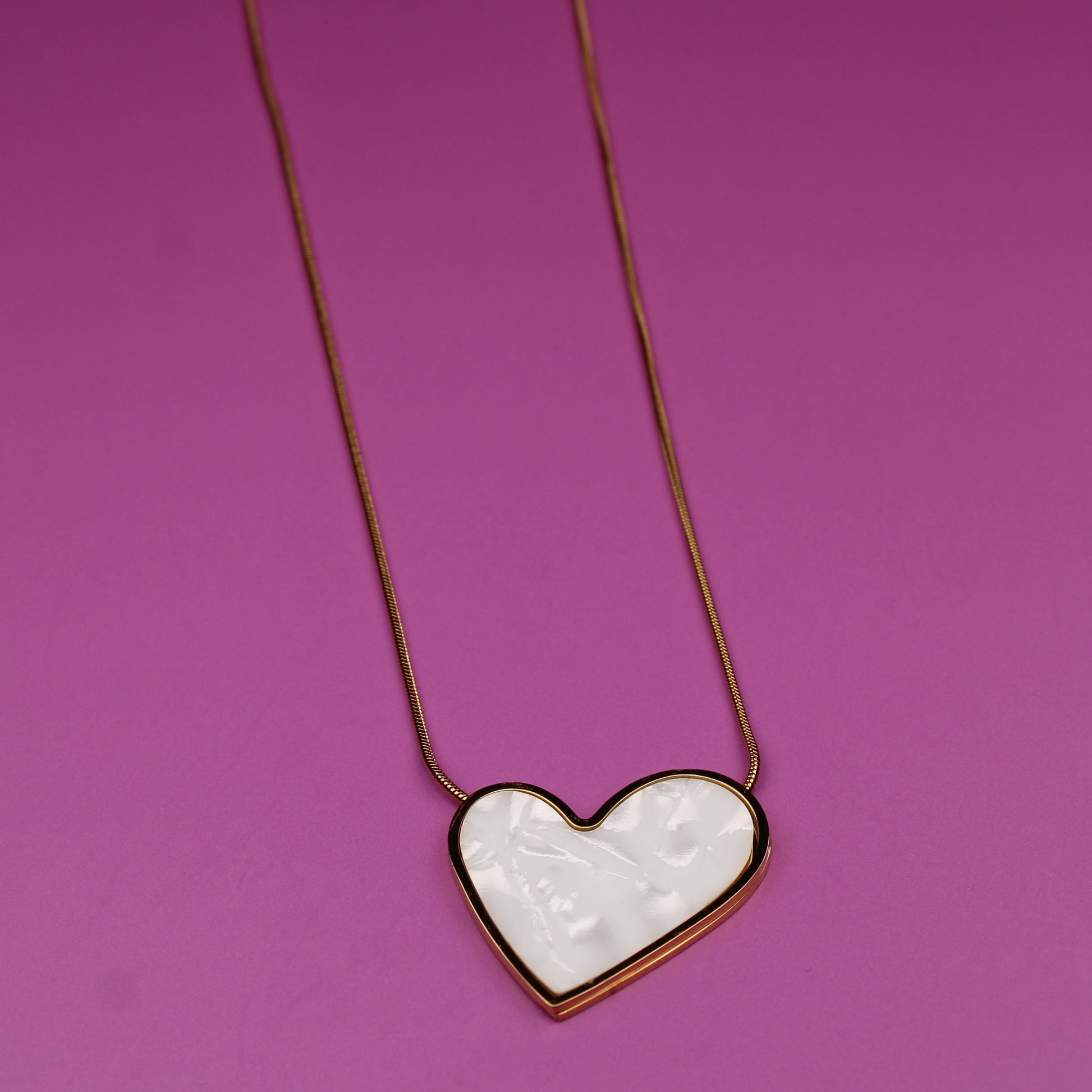 Heart-shaped pendant necklace on a pink background