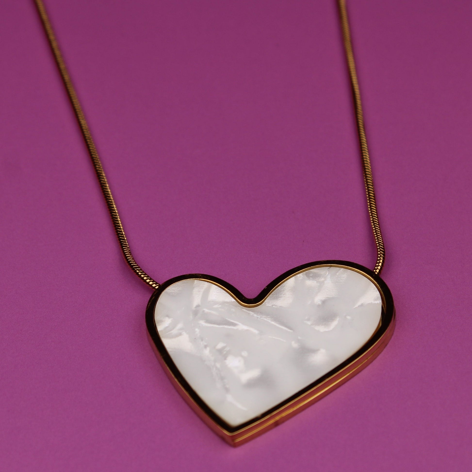 Heart-shaped pendant necklace on a pink background