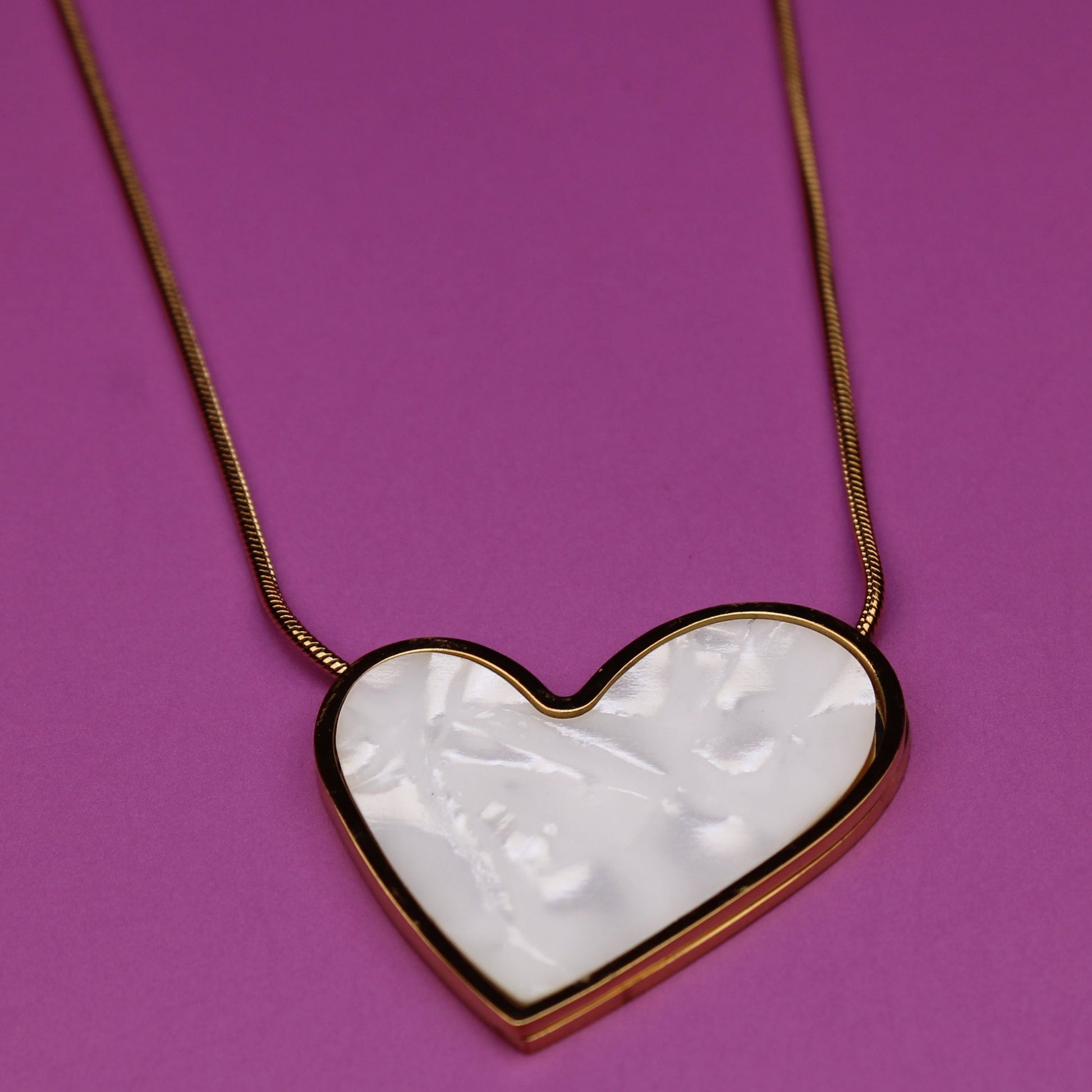 Heart-shaped pendant necklace on a purple background