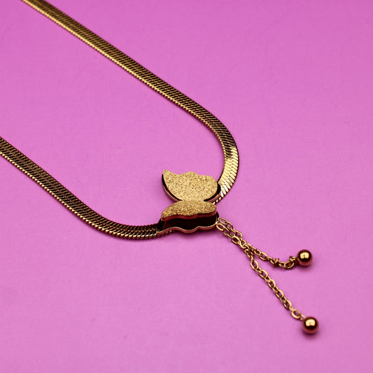 Gold necklace with a leaf pendant on a pink background