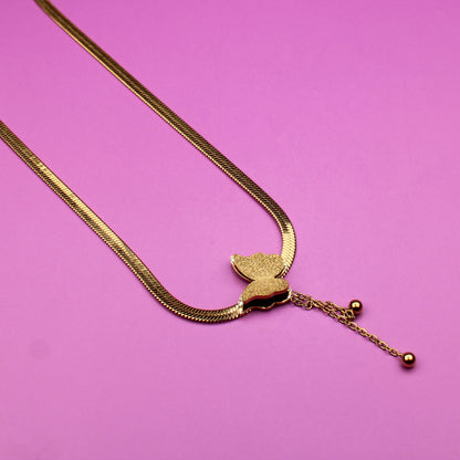 Gold necklace with a heart pendant on a pink background