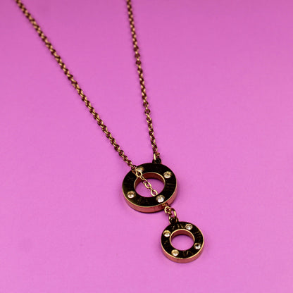 Gold necklace with circular pendants on a pink background
