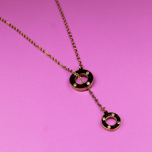 Rose gold necklace with heart-shaped pendant on a pink background