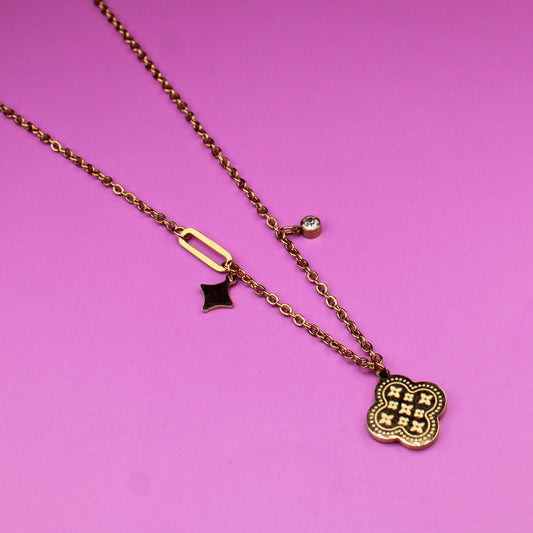 Gold necklace with two charms on a pink background